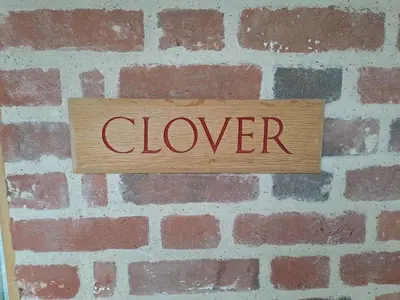 a sign on a brick wall with the word clover at Low Farm Barn, a family and dog friendly haven in Brundish