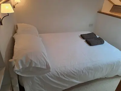 a bed with white sheets and pillows in a room at Low Farm Barn, a family and dog friendly haven in Brundish