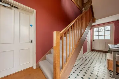 a staircase in a home with red walls and a white door at Belchamp Hall Hayloft and Stables in Belchamp Otten