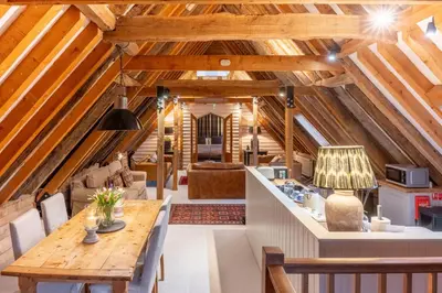 an attic kitchen and living room with wooden beams at Belchamp Hall Hayloft and Stables in Belchamp Otten