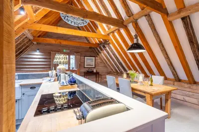 a kitchen with wooden ceilings and a table and chairs at Belchamp Hall Hayloft and Stables in Belchamp Otten