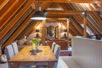 a dining room with a wooden table and chairs at Belchamp Hall Hayloft and Stables in Belchamp Otten
