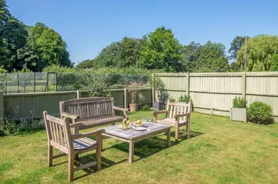 two wooden benches and a table in a garden at Belchamp Hall Hayloft and Stables in Belchamp Otten