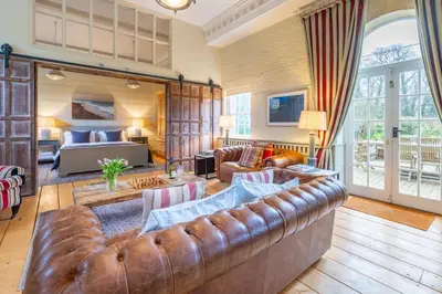 a living room with a brown leather couch at Belchamp Hall Hayloft and Stables in Belchamp Otten