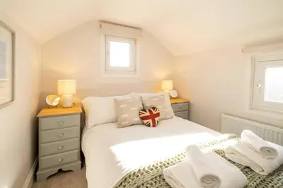a bedroom with a white bed and two windows at 7 Prospect Place - Aldeburgh Coastal Cottages in Leiston