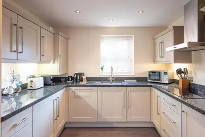 a kitchen with white cabinets and a sink at 9 Reade Court, Aldeburgh in Aldeburgh