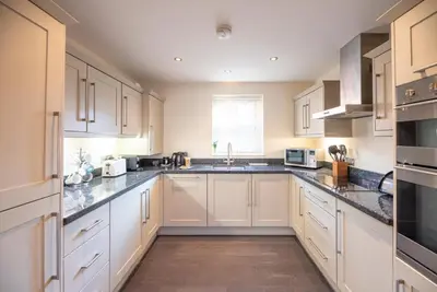 a kitchen with white cabinets and a sink at 9 Reade Court, Aldeburgh in Aldeburgh