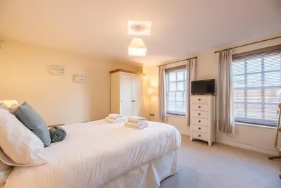 a bedroom with a white bed and a television at 9 Reade Court, Aldeburgh in Aldeburgh