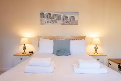 a bedroom with a large white bed with two lamps at 9 Reade Court, Aldeburgh in Aldeburgh