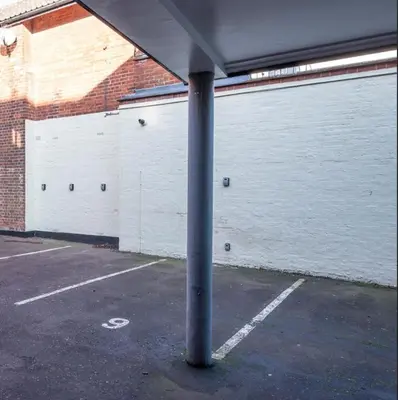 a pole in a parking lot next to a white garage at 9 Reade Court, Aldeburgh in Aldeburgh