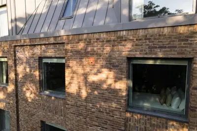 a brick building with three windows and a reflection of a building at Wilde Cambridge City Centre in Cambridge