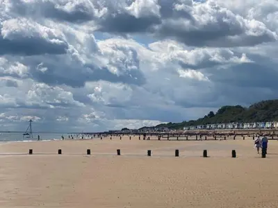two people walking on a beach with a pier at 6 Beds 2 Sofa bed Family friendly - unlimited Wi-Fi, Warm, Cozy Sun decking Caravan at Seawick Holiday Park in Saint Osyth