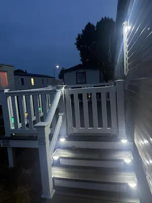 a white bench on a porch with lights on it at 6 Beds 2 Sofa bed Family friendly - unlimited Wi-Fi, Warm, Cozy Sun decking Caravan at Seawick Holiday Park in Saint Osyth