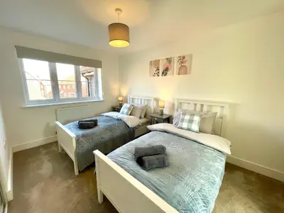 a bedroom with two beds and a window at New Modern 2 Bed with parking in BISHOPS STORTFORD, close to Stansted Airport! in Bishops Stortford