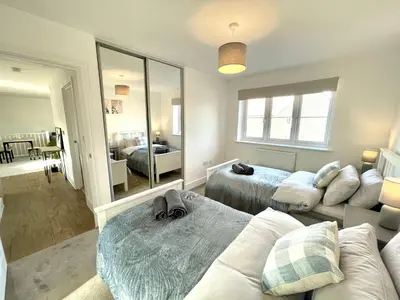 a bedroom with two beds and a mirror at New Modern 2 Bed with parking in BISHOPS STORTFORD, close to Stansted Airport! in Bishops Stortford