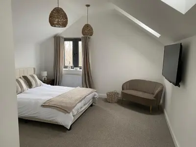 a bedroom with a bed and a chair and a television at Number Forty One in Sudbury