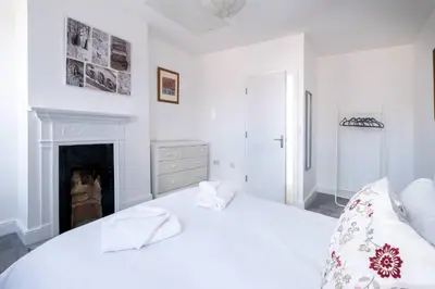 a white bedroom with a bed and a fireplace at 2 Volunteer House, Leiston - Aldeburgh Coastal Cottages in Leiston