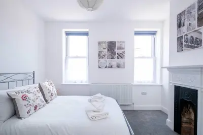 a white bedroom with a bed and a fireplace at 2 Volunteer House, Leiston - Aldeburgh Coastal Cottages in Leiston