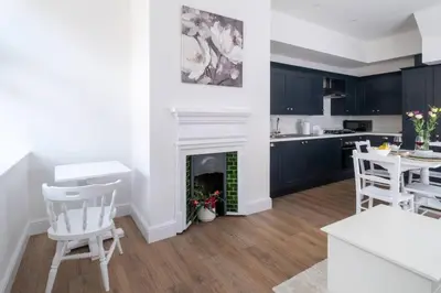 a kitchen and living room with a fireplace and a table at 2 Volunteer House, Leiston - Aldeburgh Coastal Cottages in Leiston