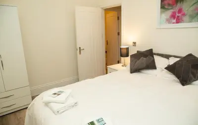 a white bedroom with two beds with towels on them at Seaview Apartments - 30 Marine Parade, Harwich - Perfect for business & long term stays in Harwich
