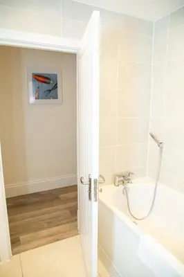 a white bathroom with a tub and a sink at Seaview Apartments - 30 Marine Parade, Harwich - Perfect for business & long term stays in Harwich
