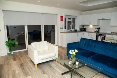 a living room with a blue couch and a white chair at Seaview Apartments - 30 Marine Parade, Harwich - Perfect for business & long term stays in Harwich