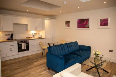 a living room with a blue couch and a kitchen at Seaview Apartments - 30 Marine Parade, Harwich - Perfect for business & long term stays in Harwich