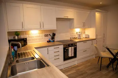 a kitchen with white cabinets and a sink and a table at Seaview Apartments - 30 Marine Parade, Harwich - Perfect for business & long term stays in Harwich