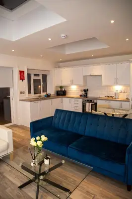 a living room with a blue couch and a kitchen at Seaview Apartments - 30 Marine Parade, Harwich - Perfect for business & long term stays in Harwich