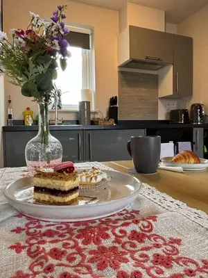 a table with a plate of cake and a vase with flowers at Cosy 1-Bed Apt in Newmarket with Parking in Newmarket