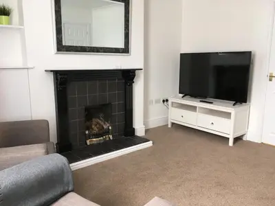 a living room with a fireplace and a flat screen tv at Cambridge Water House Apartments in Cambridge