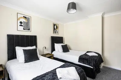a hotel room with two beds with black headboards at The House In Defoe Rd - 3br 1bath W Free Parking in Ipswich