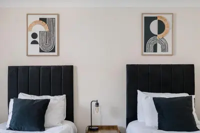 two beds with black headboards in a bedroom at The House In Defoe Rd - 3br 1bath W Free Parking in Ipswich