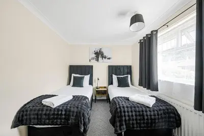 two twin beds in a room with a window at The House In Defoe Rd - 3br 1bath W Free Parking in Ipswich