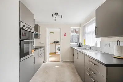 a kitchen with white cabinets and a black counter top at The House In Defoe Rd - 3br 1bath W Free Parking in Ipswich