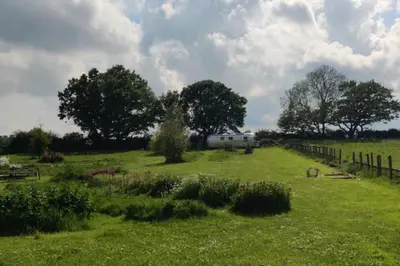 a field with a camper in the middle of it at Bury - Lodge - Sleeps 2 - Parking in Great Welnetham