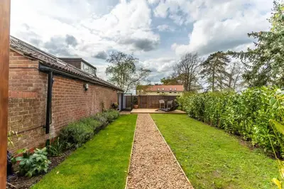 a garden with a brick building and a pathway at Modern self contained one bedroom with garden in Sheering