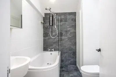 a bathroom with a shower and a tub and a sink at Modern self contained one bedroom with garden in Sheering
