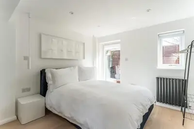 a white bedroom with a bed and a window at Modern self contained one bedroom with garden in Sheering