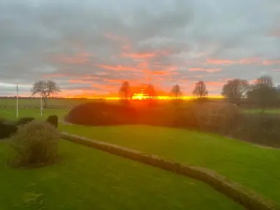 a view of a field with the sunset in the background at North Farm fits 1-6 people in Sawston