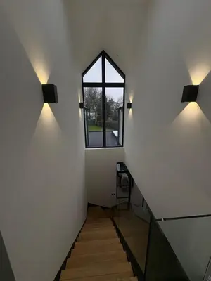 a staircase with two lights on the wall and a window at House of Hertfordshire in Datchworth