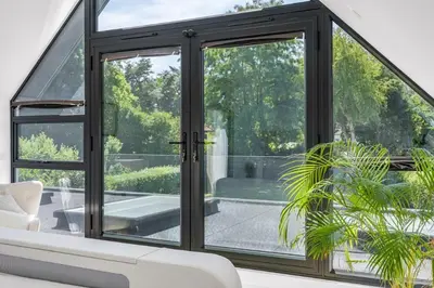 an open glass door in a living room with a plant at House of Hertfordshire in Datchworth