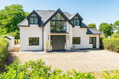 a white house with black windows and a driveway at House of Hertfordshire in Datchworth