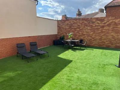 a patio with chairs and a table on grass at Seaview House with Sea View Brand New- 3 Bedrooms - Harwich, Dovercourt in Lancing