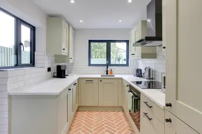 a white kitchen with white cabinets and a window at Luxury Two Bedroom Cottage - Bishops Stortford in Bishops Stortford