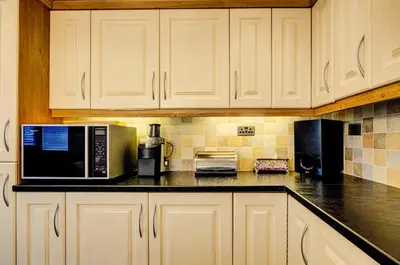 a kitchen with white cabinets and a black counter top at Luxury - 4 BHK Semi Detached House in Chelmsford