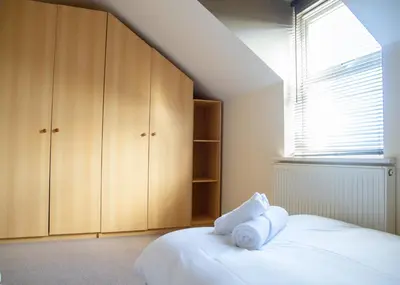 a bedroom with wooden cabinets and a bed with towels at 4x Bed Elegant Home with Parking in Ely