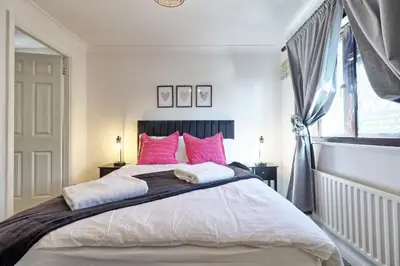 a bedroom with a large bed with pink pillows at 4br 2bath House With Free Parking In Rivenhall in Rivenhall