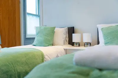 a bedroom with two beds with green and white pillows at Charlotte House 2bed 2bath Retreat For 6 Guests in Ipswich