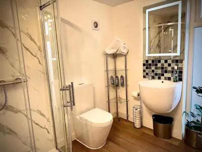 a bathroom with a toilet and a glass shower at Beautiful 2 Bedroom Barn -Stansted Airport 2 miles in Elsenham